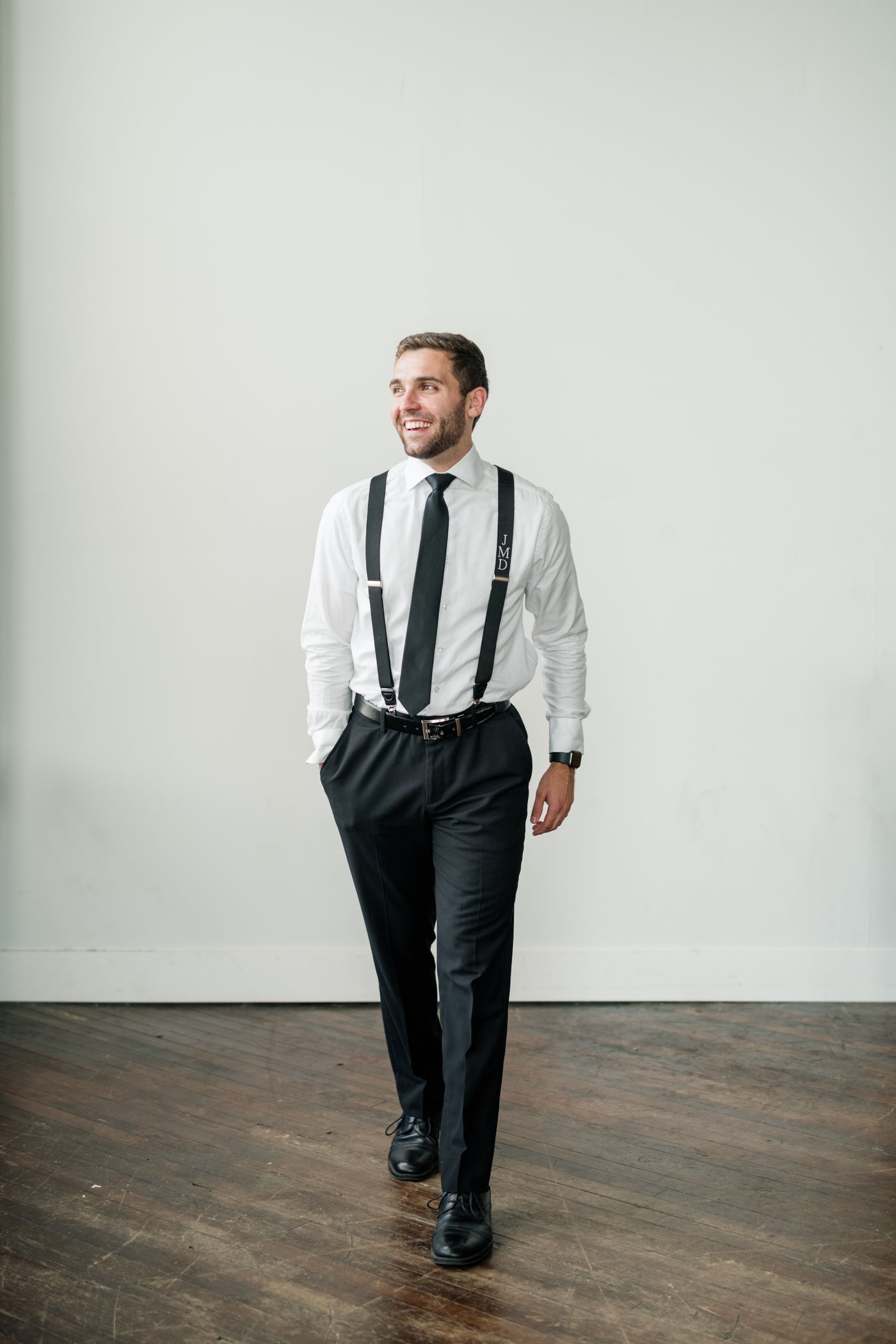 groom walking wearing monogram suspender and dress pants