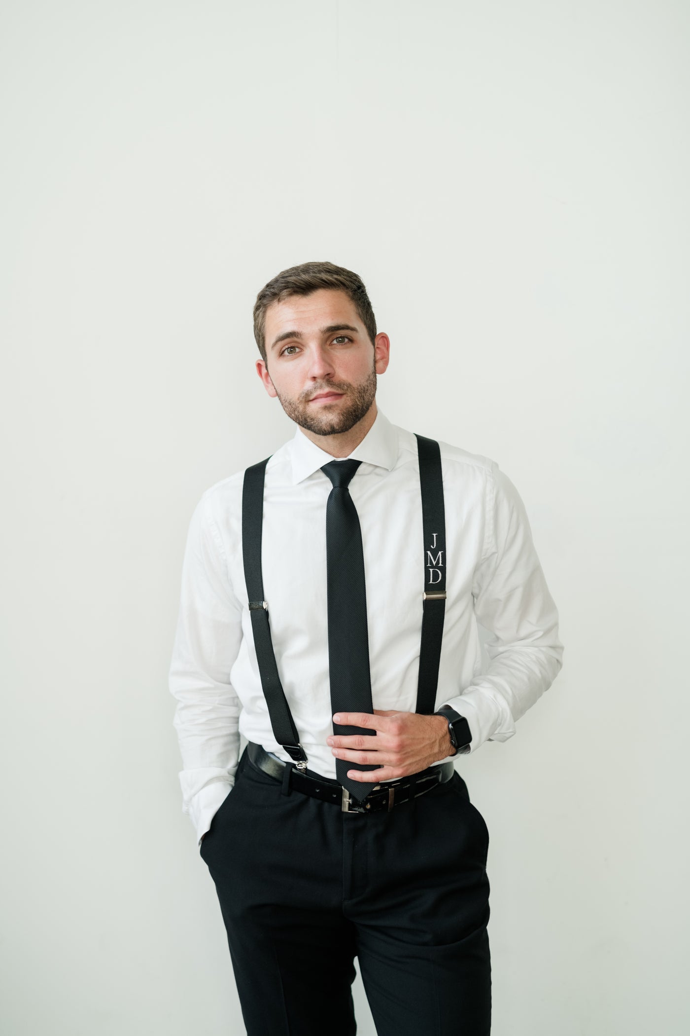 man wearing black tie and black suspender with embroidered monogram